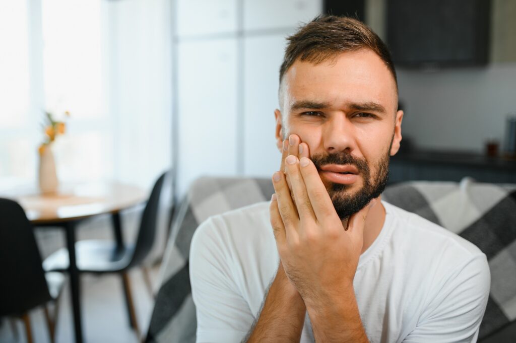 man in pain, needing tooth extraction from Birk Dental in Creve Coeur, MO.